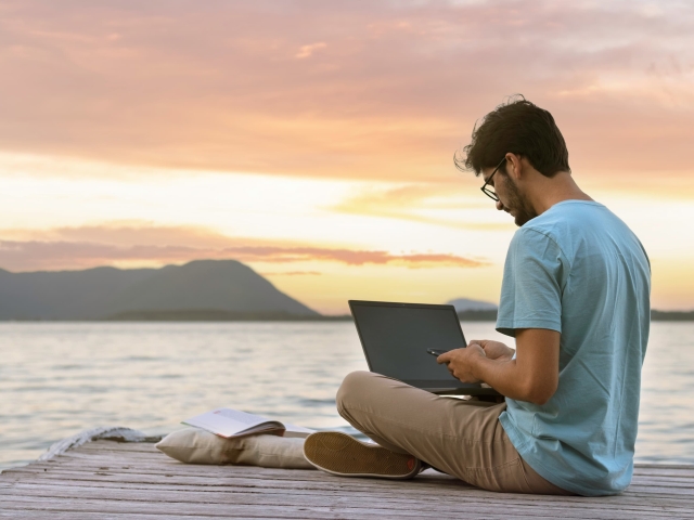 Image of a man sitting on a deck with a laptop